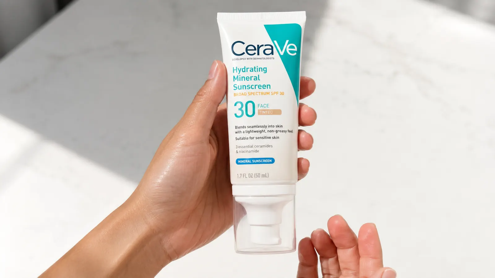 CeraVe Tinted Mineral Sunscreen tube being held against a clean white background