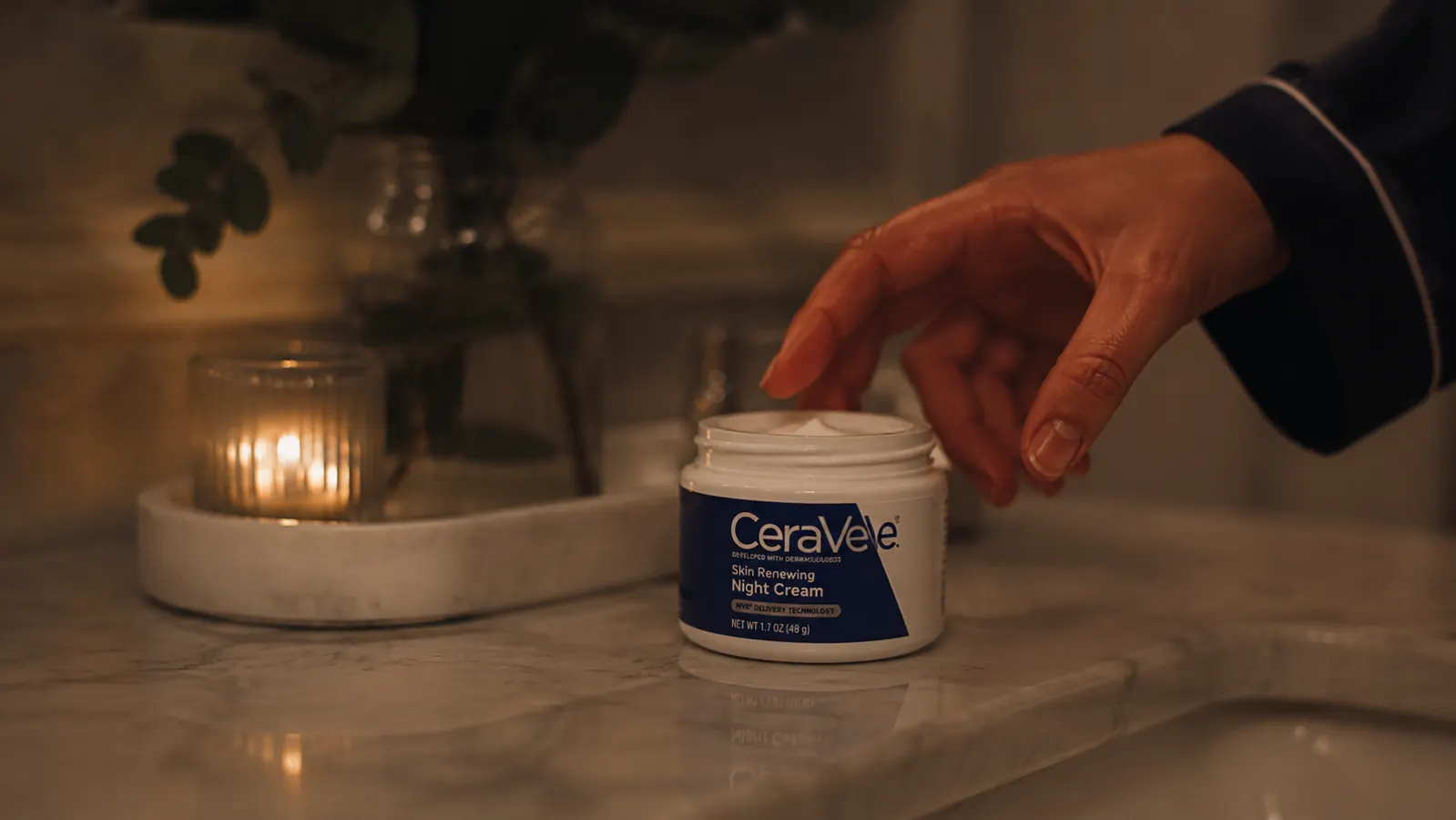 CeraVe Skin Renewing Night Cream jar on a marble bathroom counter with soft warm lighting at night