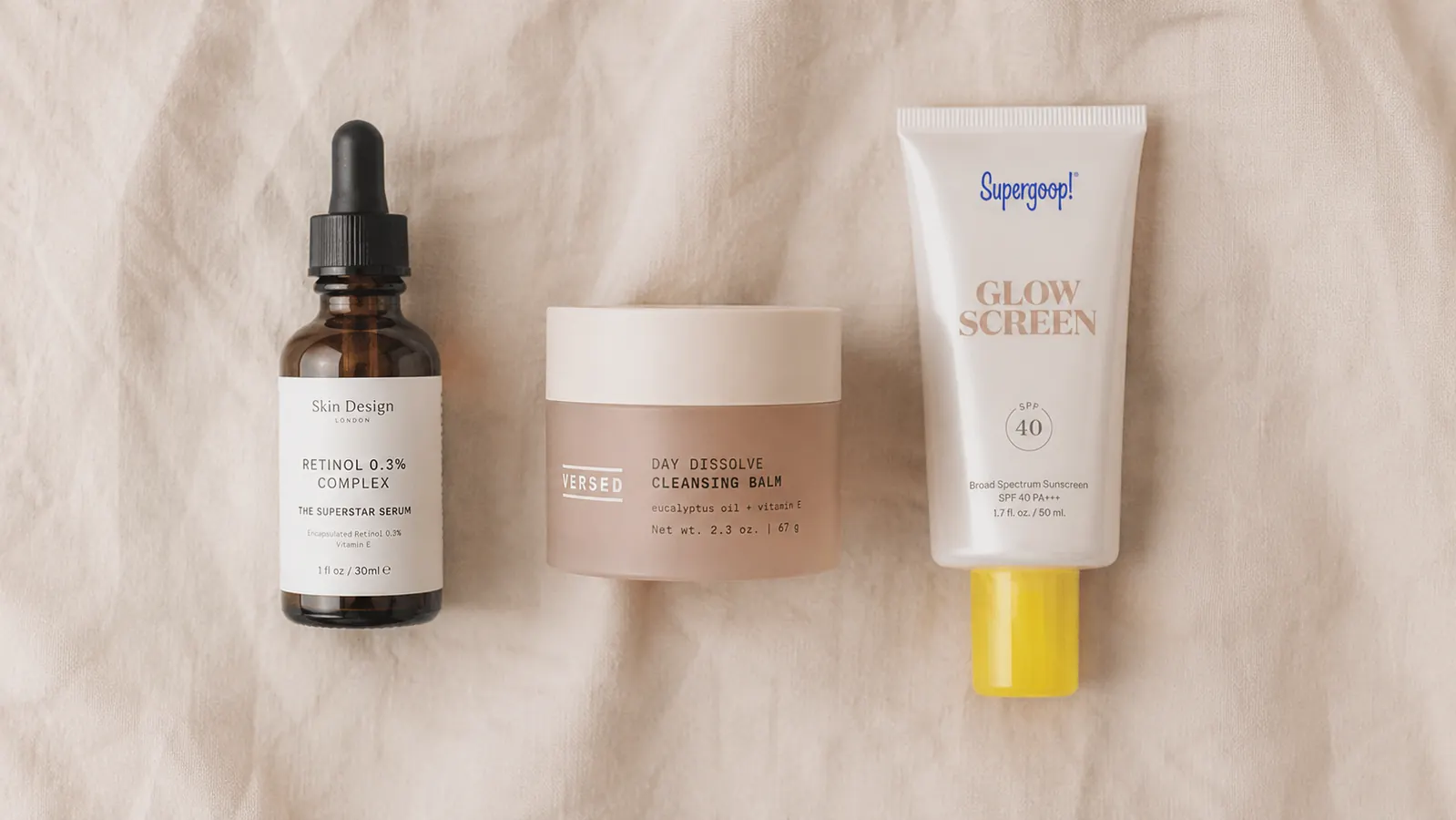 A simple flat-lay showing a vitamin C serum, a moisturizer, and a sunscreen tube in the correct layering order left to right