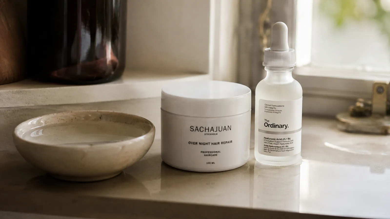 Small ceramic bowl of water beside a moisturizer jar and serum bottle on a clean bathroom shelf