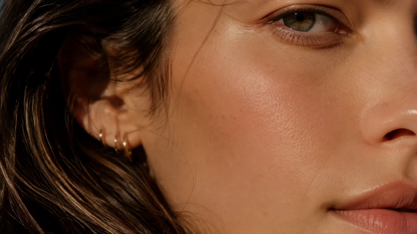 Close-up of a woman's cheek showing clear, even skin tone in warm natural light